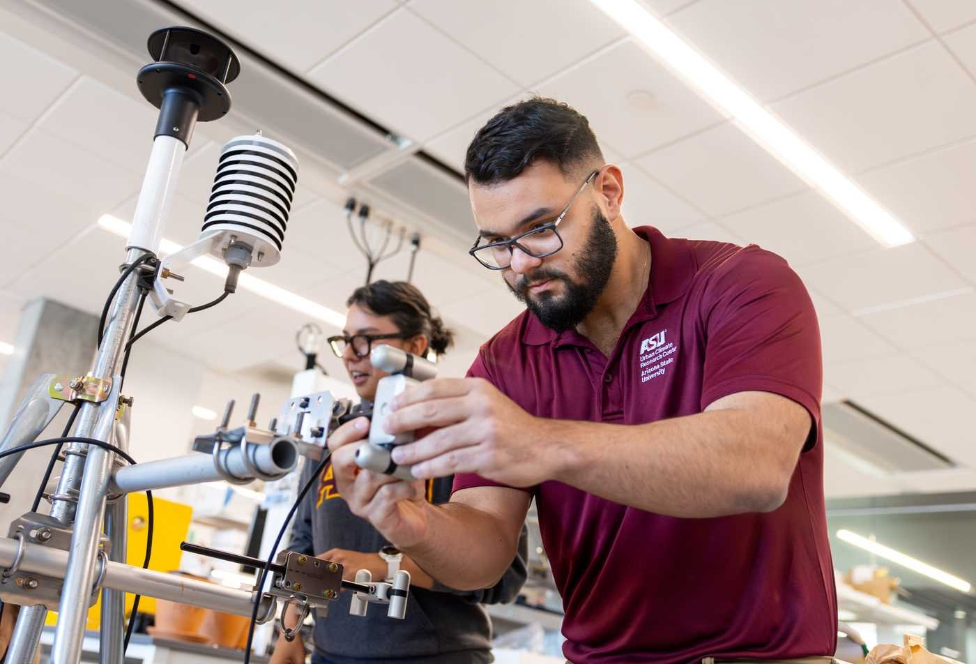 Students adjust climate and weather monitoring instruments in a lab, demonstrating hands-on learning in the certificate in Atmospheric Sciences.