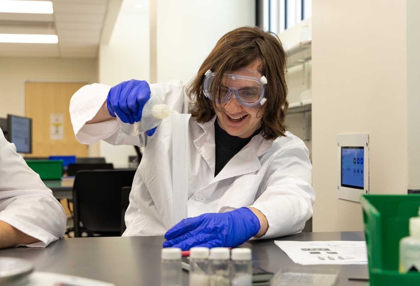 A researcher handles equipment in a cleanroom, supporting molecular research in ASU's Biochemistry, BA program.