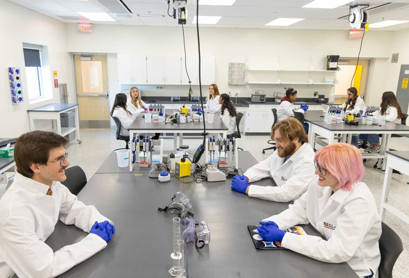 A group of students sit in a large lab room, showcasing hands-on learning in the minor in Biochemistry.