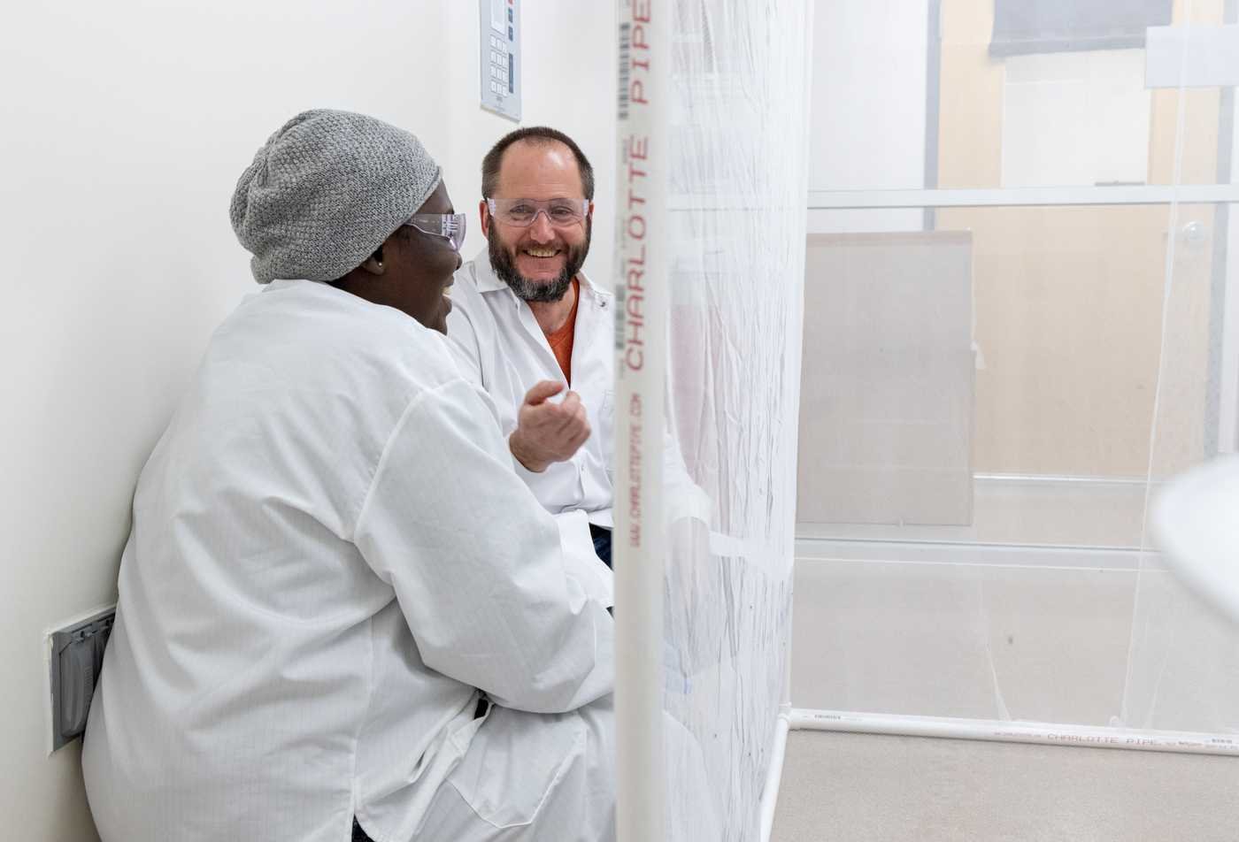 Two researchers in lab coats discuss their project, demonstrating collaborative research ing the Molecular and Cellular Biology, PhD.