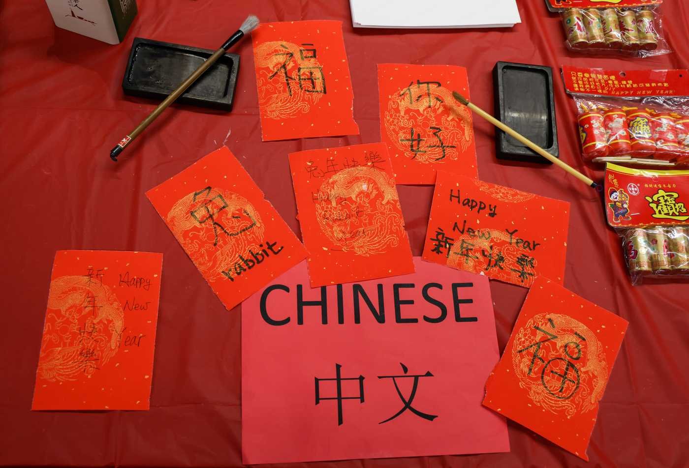 Vibrant red papers with Chinese caligraphy set atop a red table, showcasing the field explored in the BA in Asian Languages (Chinese).