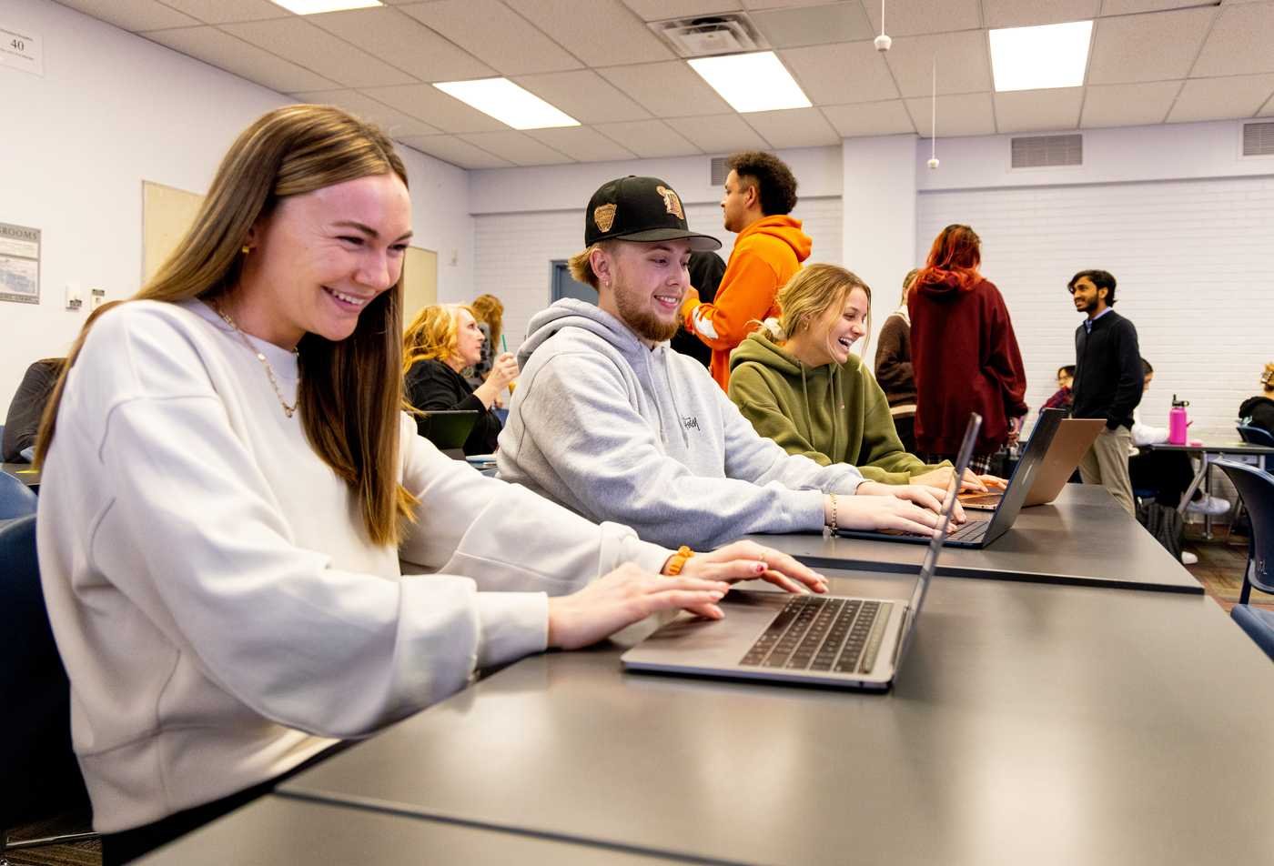 Students work on laptops in a classroom, building communication skills in ASU's Communication, BS program.