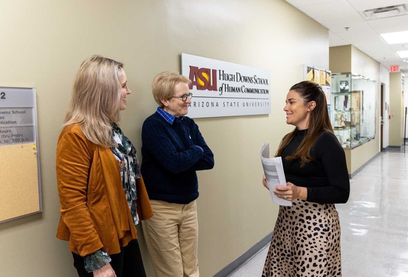 Three staff memebrs engage in discussion in the Hugh Downs School of Human Communication, demonstrating expertise in the minor in Communication