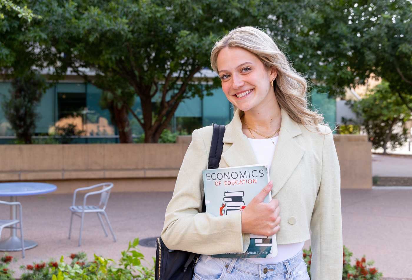 A student holds an economics textbook on campus, reflecting economic study in ASU's Economics, BS program.