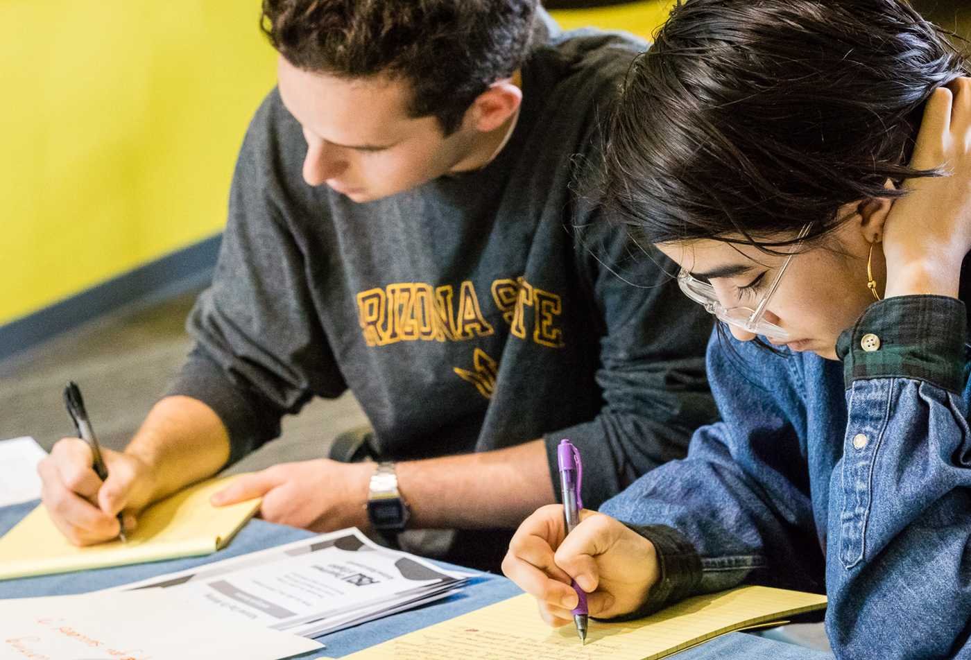 Students write together at a table, developing storytelling skills in ASU's English (Creative Writing), BA program.