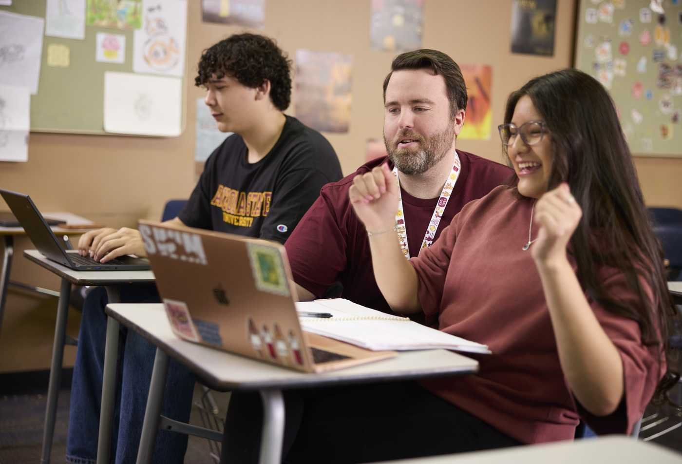 An instructor assists a student on a laptop, showing the collaborative learning in the minor in English - Linguistics.