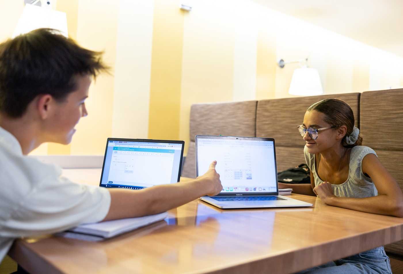 Students compare laptop work at a table, developing composition skills in ASU's English (Writing, Rhetorics and Literacies), BA program.