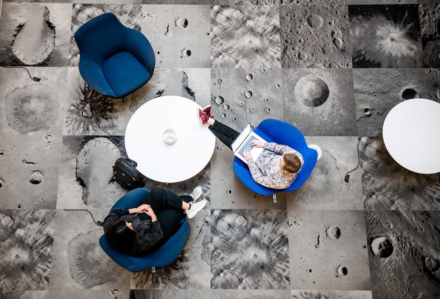 Students study over a pattern of images of the moon, symbolizing the field explored in the Exploration Systems Design (Systems Engineering), MS.