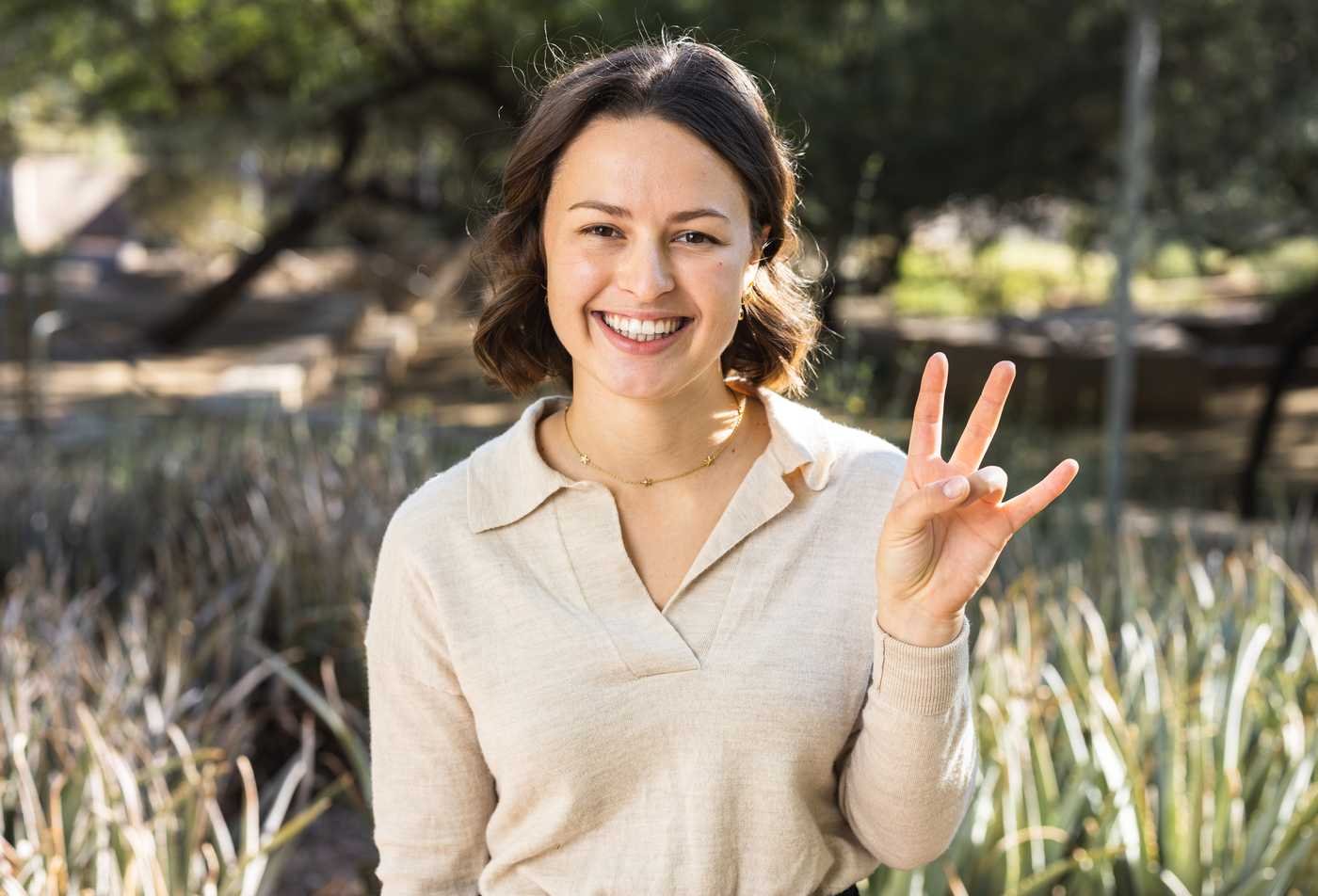 A student smiles and flashes the ASU pitchfork gesture, demonstrating the expertise gained in the Exploration Systems Design (Sensor Networks), PhD.