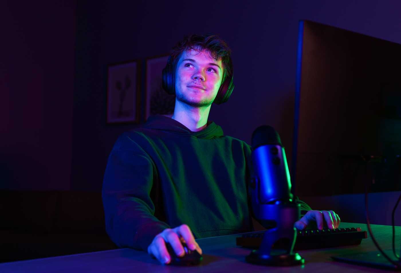 A student looks up while sitting at a computer, silhoutted by purple and green lights, symbolizing the field explore in the minor in Film and Media Studies.