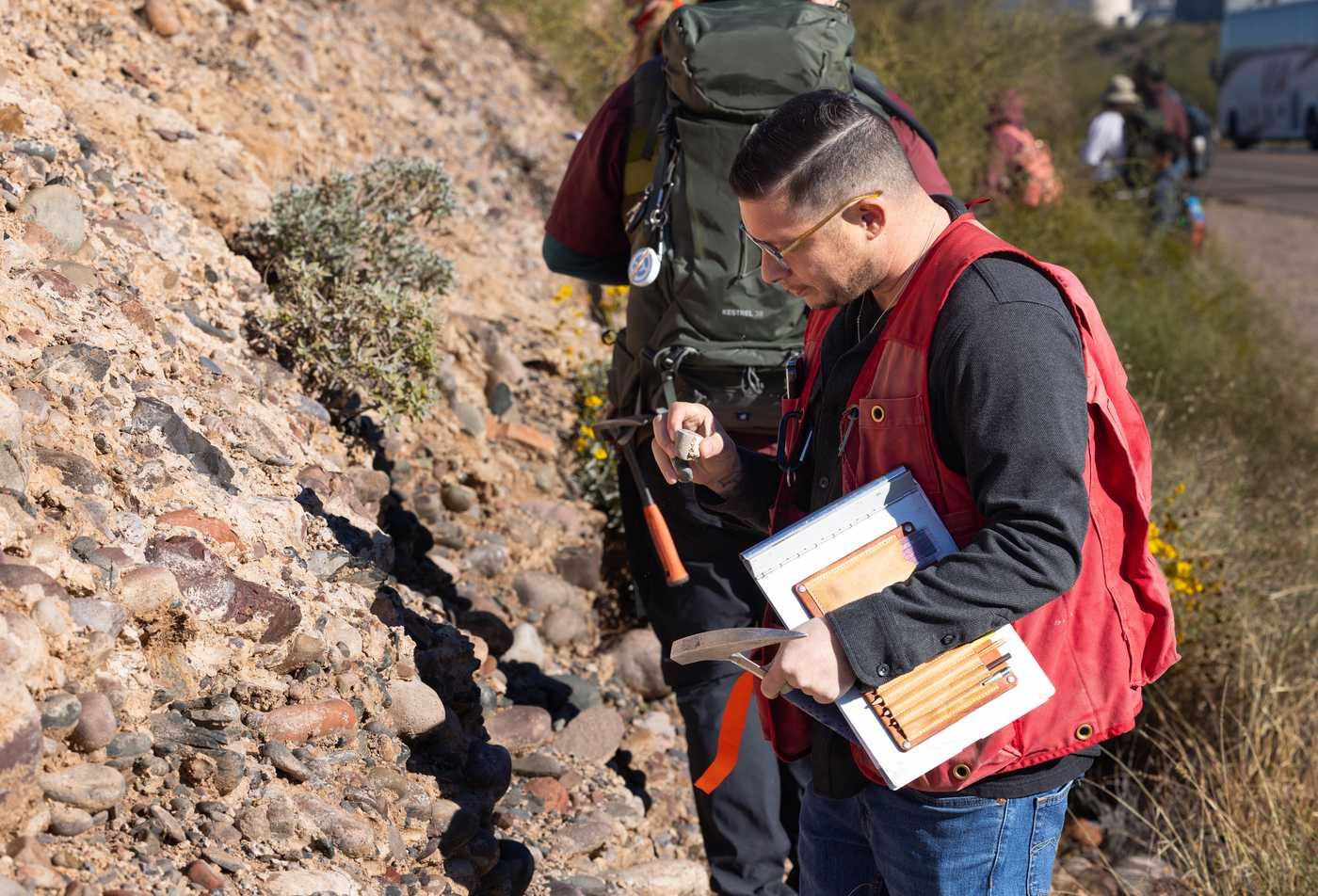 Researchers examine rocks in the field, studying physical geology in ASU's Geography, MA.