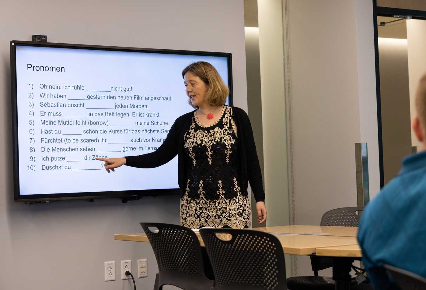 Teacher pointing at the board with German written, teaching her class grammar in the German, MA.