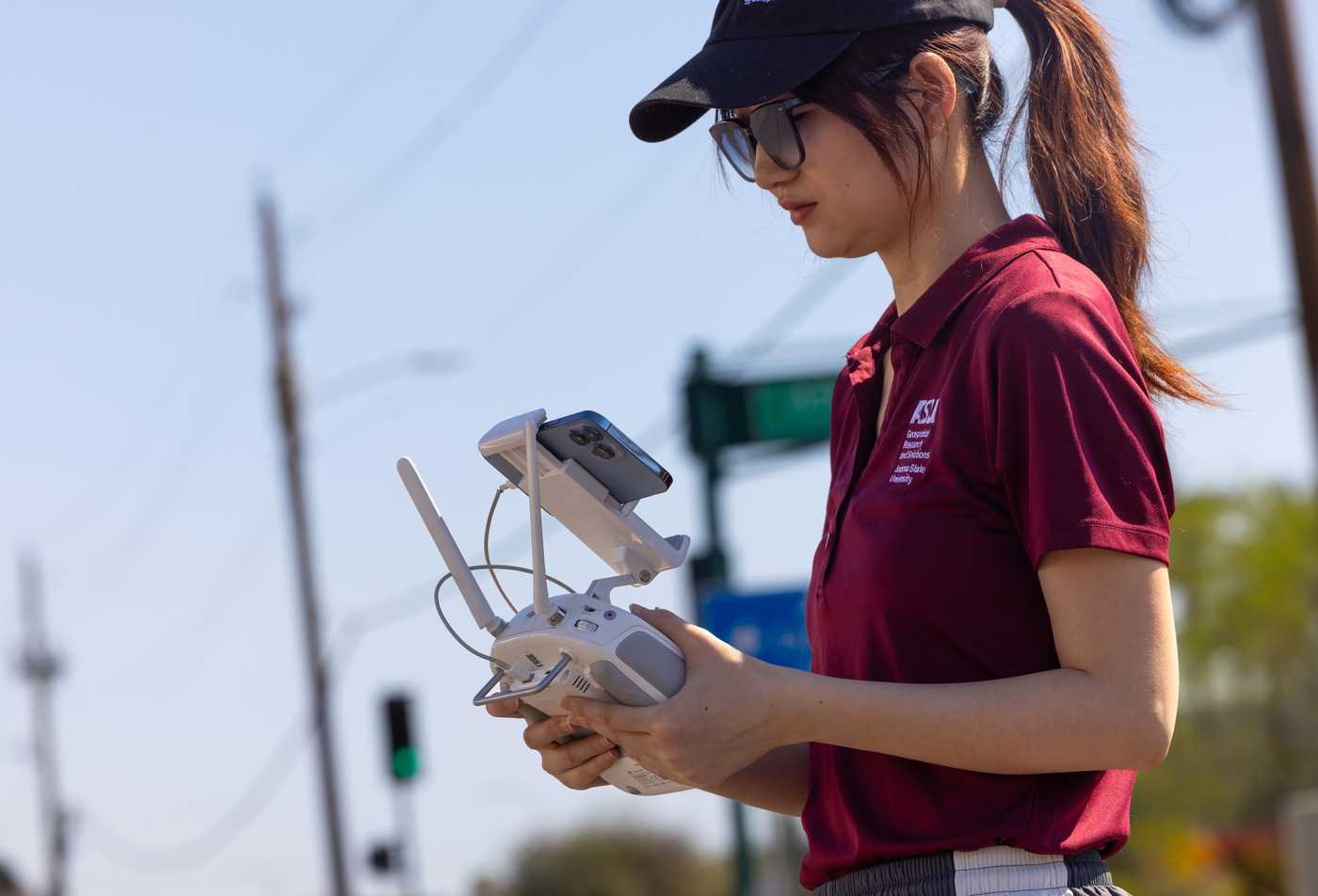 An student operates a drone controller during outdoor fieldwork, demonstrating hands-on learning in the Geographic Information Science, PhD.