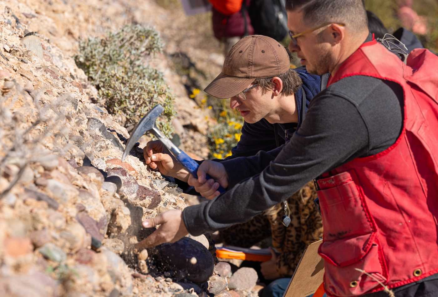 Two students looking at rocks, digging and analyzing the earth, showcasing the field explored in the Geological Sciences minor.
