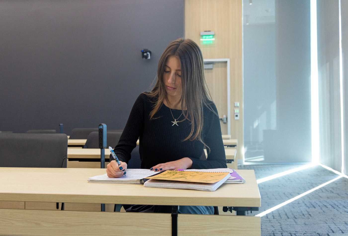 A student writes in her notebook, exploring ideas in the History and Philosophy of Science, PhD.