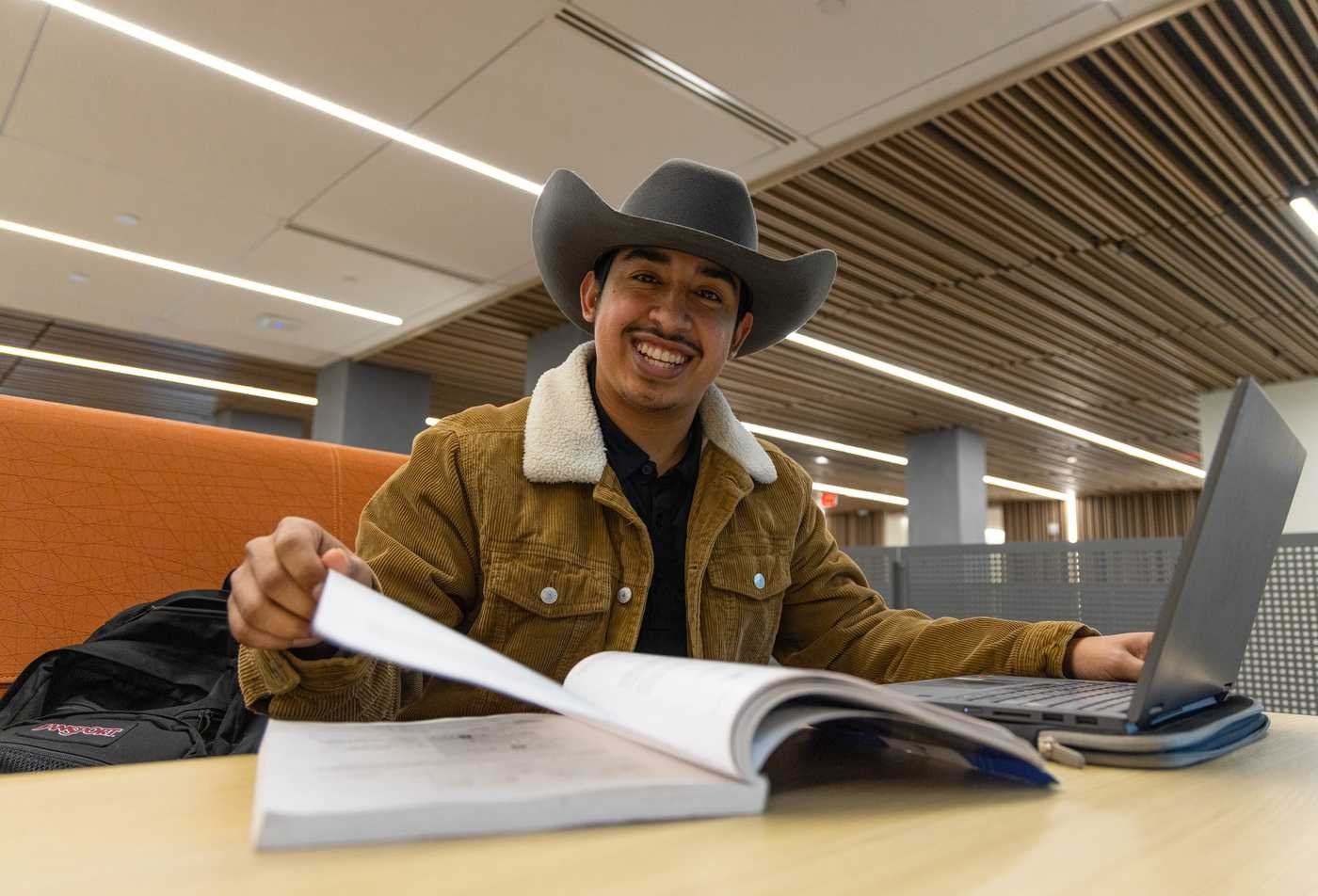 A student studies with a laptop and book, exploring global affairs in ASU's International Relations, BA program.