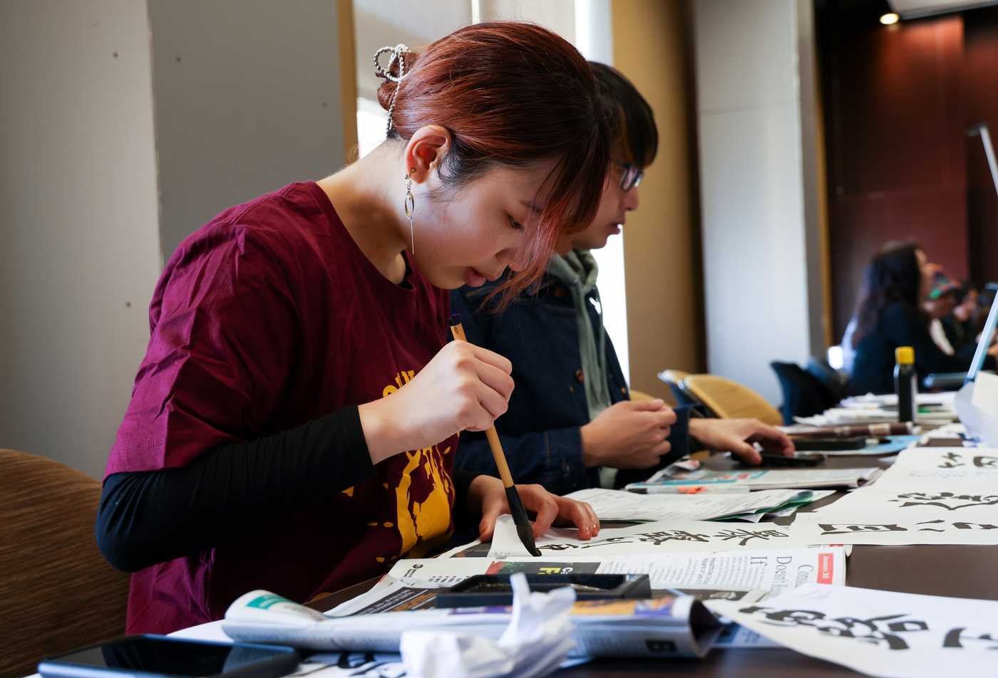 A female student works on caligraphy, demonstrating hands-learning in the BA in Asian Languages (Japanese).