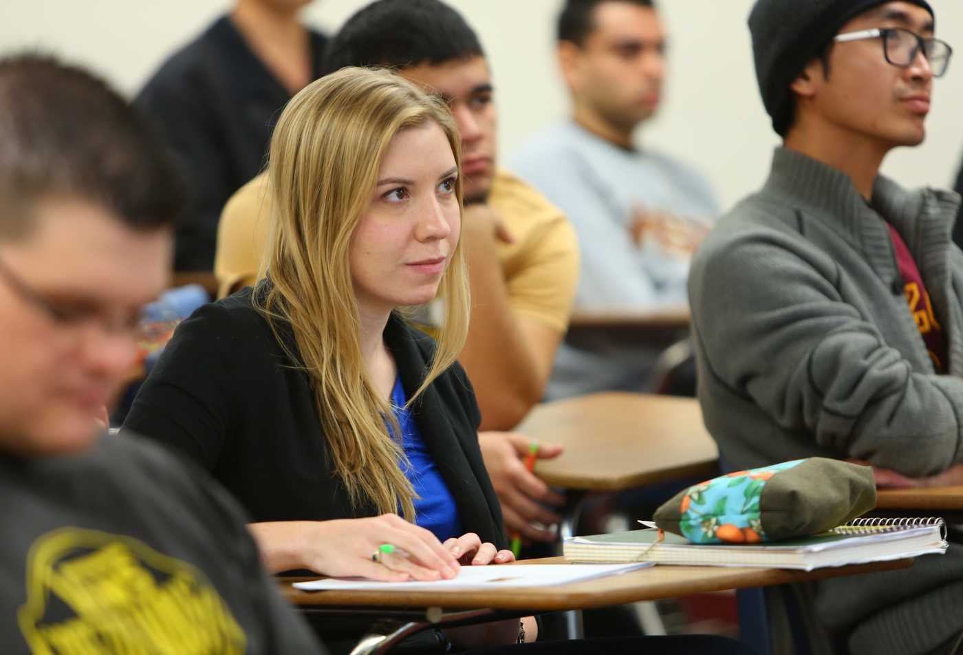 A student sits in a classroom looking forward and writing in a notebook, developing mastery of math in the minor in Mathematics.