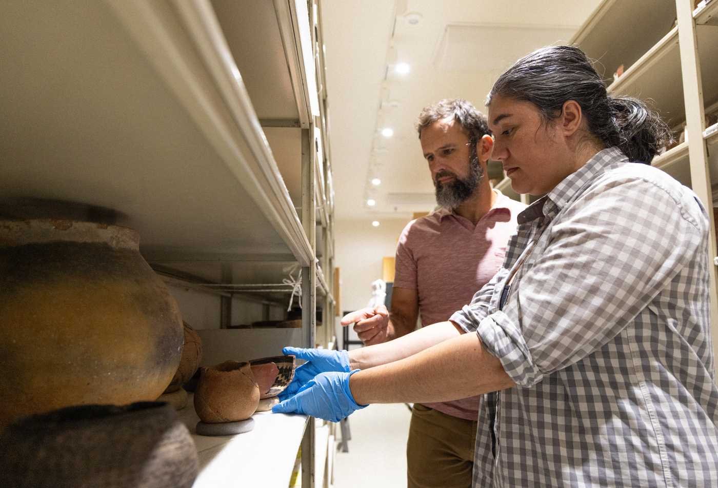 Two students examine historical artifacts within an archive, showcasing hands-on learning in the Museum Studies (Graduate Certificate).