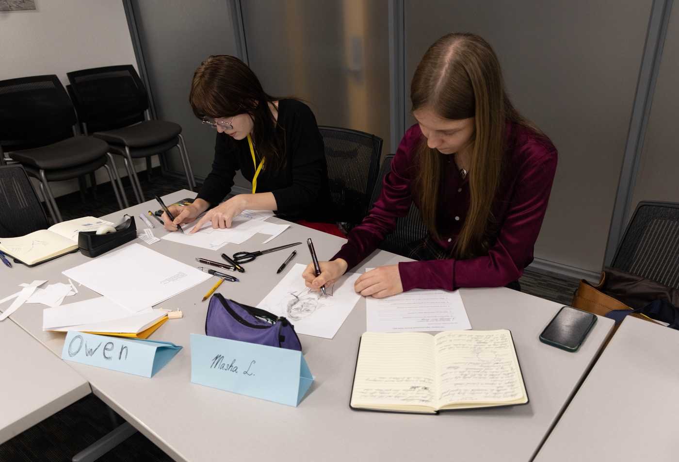 Two students write and draw in their philosophy summer camp, developing expertise in the Philosophy, PhD.