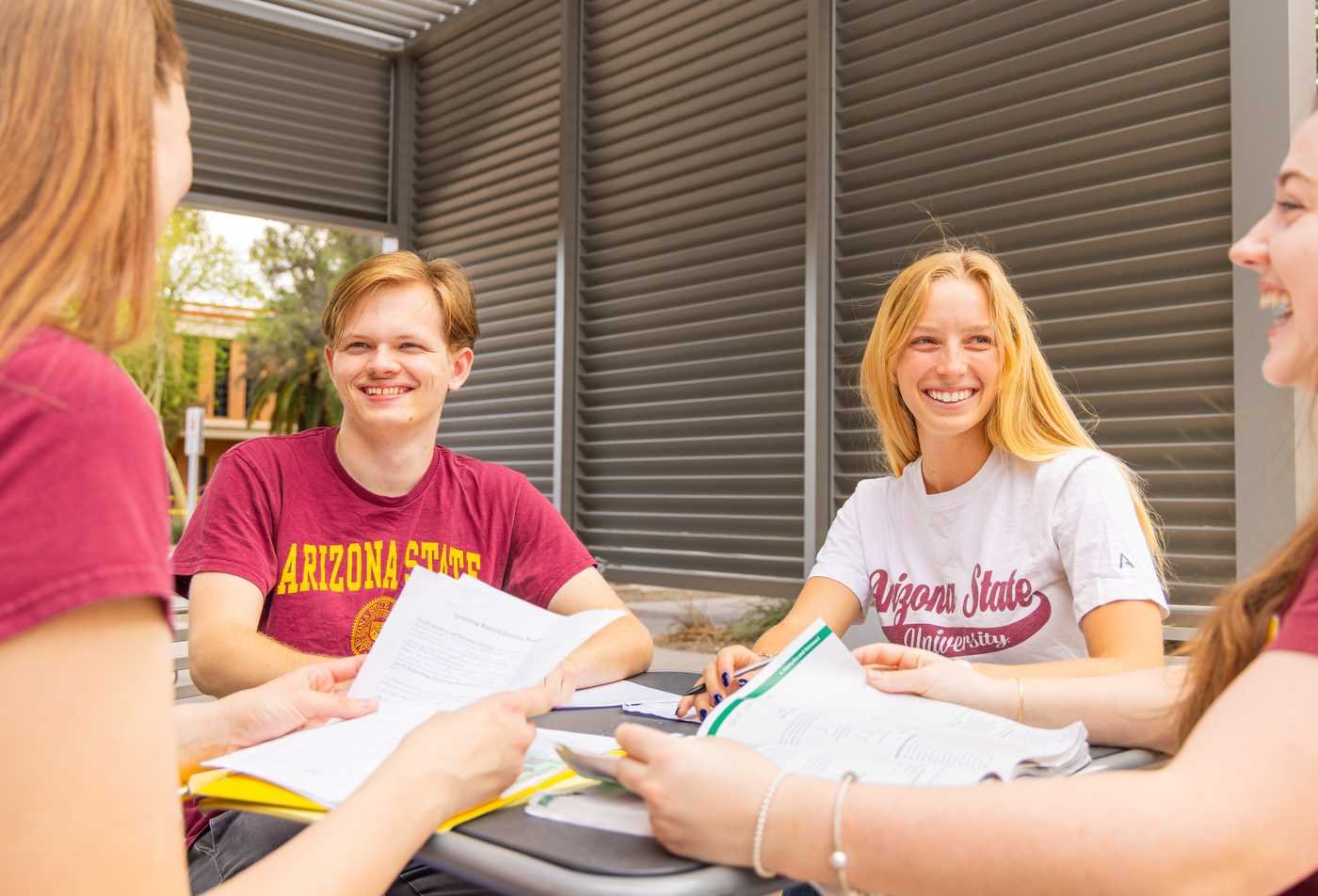 Four students in ASU shirts work together outside on campus, demonstrating collaborative learning in the minor in Philosophy.