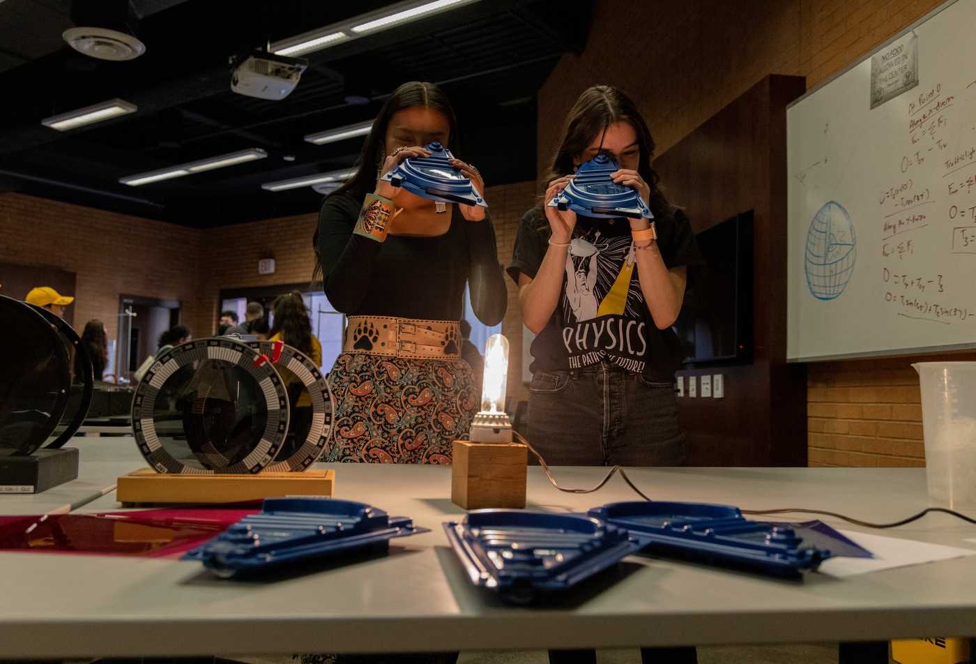 Students examine physics equipment, showcasig hands-on learning in the Physics, MS.