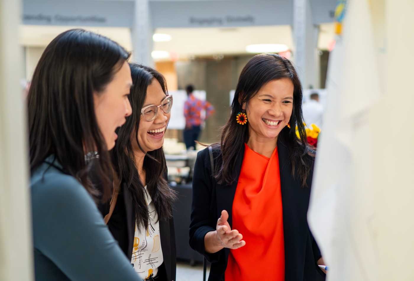 Psychology faculty members engage with a student on their poster display, showing hands-on learning in the Psychology, PhD.