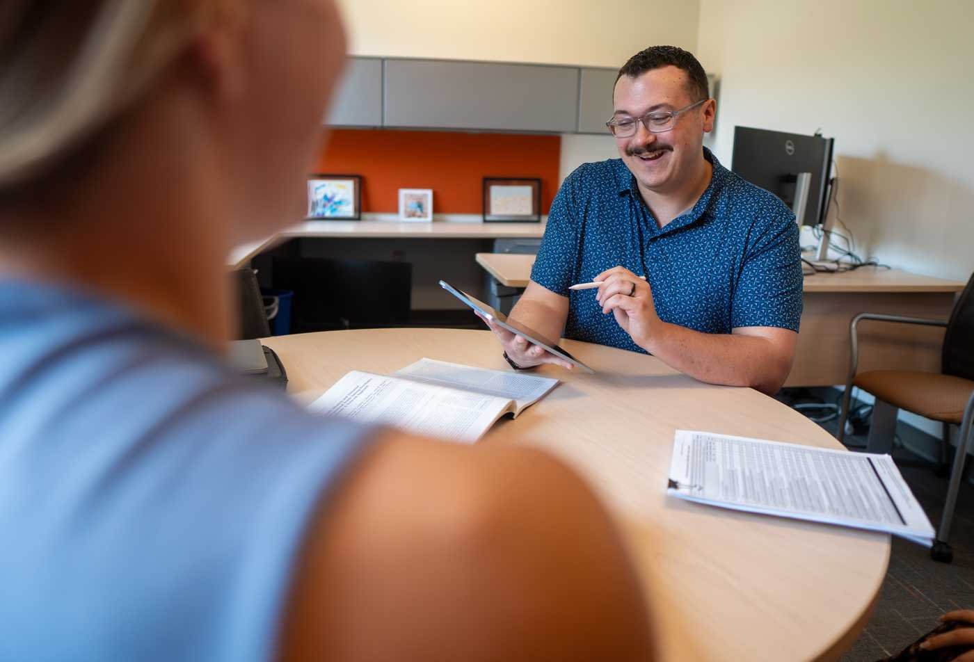A psychology faculty member meets with a student in an office setting, showcasing personalized learning in the Psychology (Clinical), PhD.