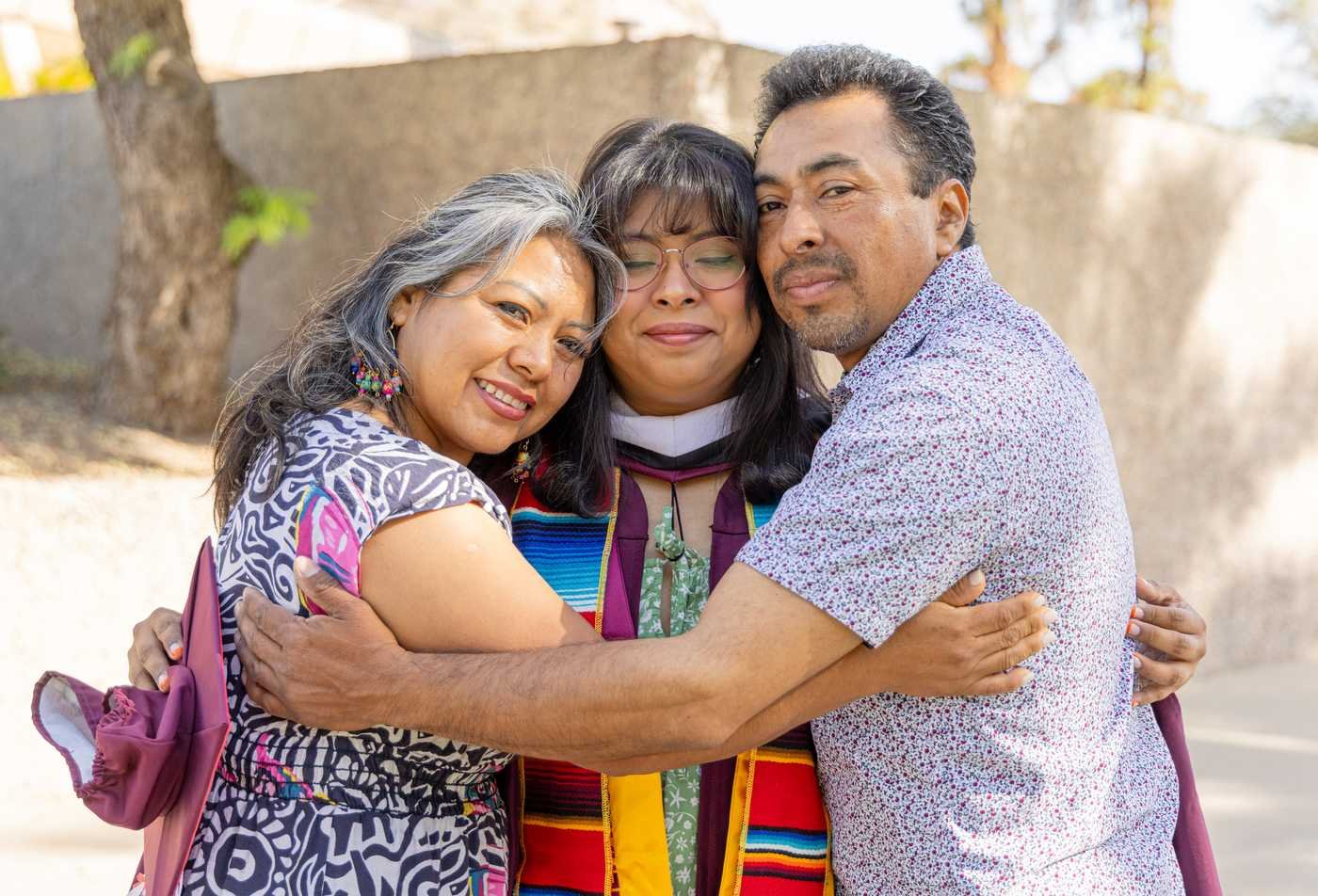 A Transborder Chicana/o and Latina/o Studies graduate is embraced by her parents.