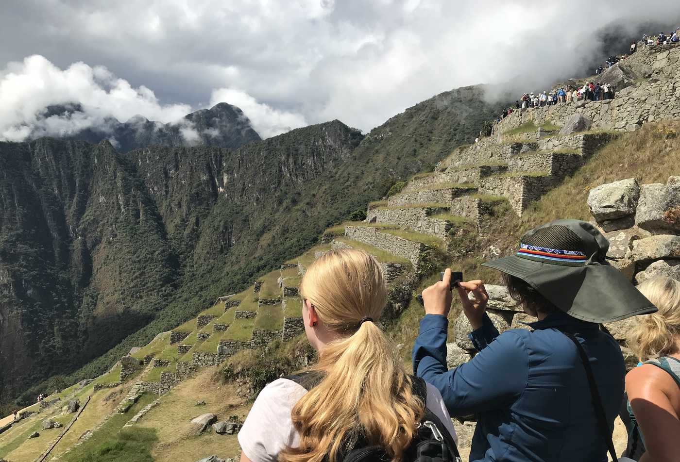 Three people sit together as they view and take a picture of ancient ruins, demonstrating hands-on learning in the PhD in Anthropology (Urbanism).
