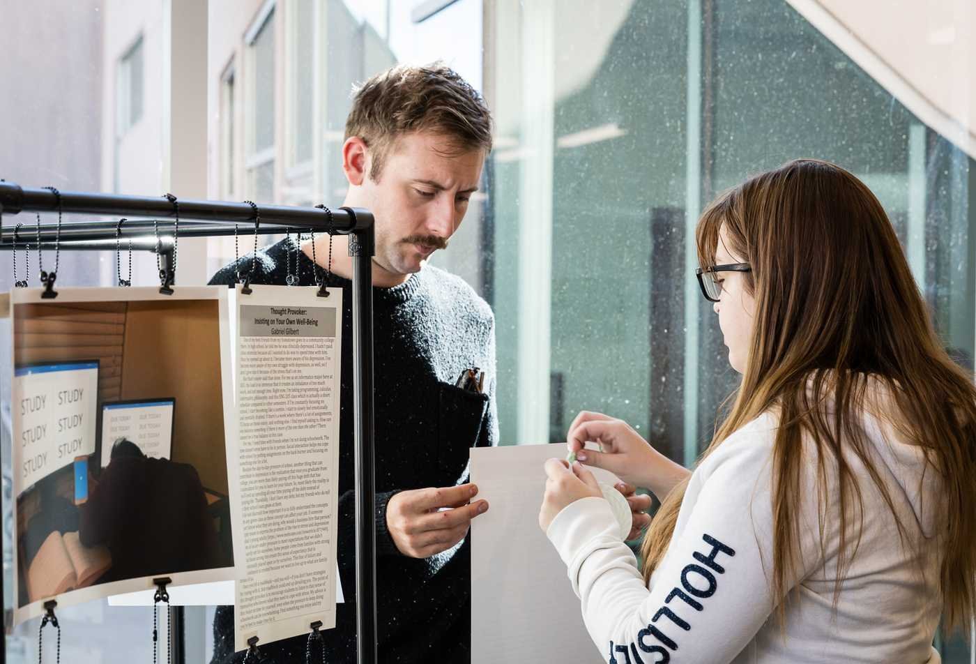 Students prepare a display for their research study, showcasing practical experience in the minor in Writing, Rhetorics and Literacies.