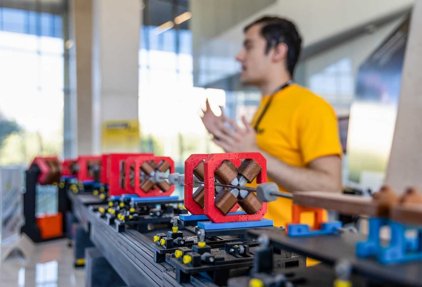 A student displays mechanical models with red frames to demonstrate physical systems, connecting hands-on exploration to ASU’s Applied Physics program