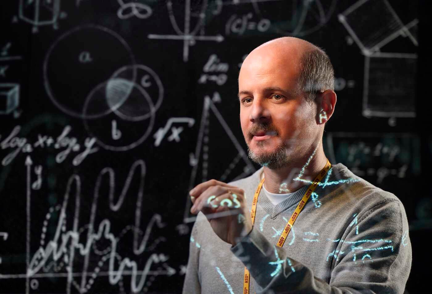 An instructor writes equations on a transparent board, demonstrating the field explored in ASU's Applied Mathematics minor.