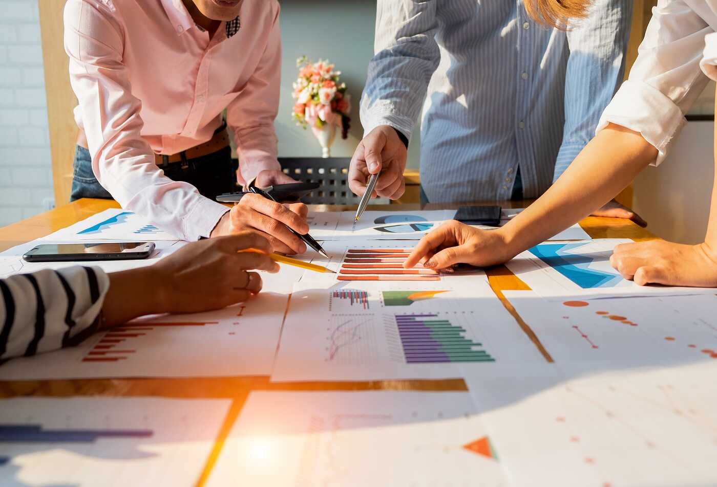 Charts spread across a table as a team reviews data, illustrating hands-on learning in ASU’s Applied Science in Project Management program