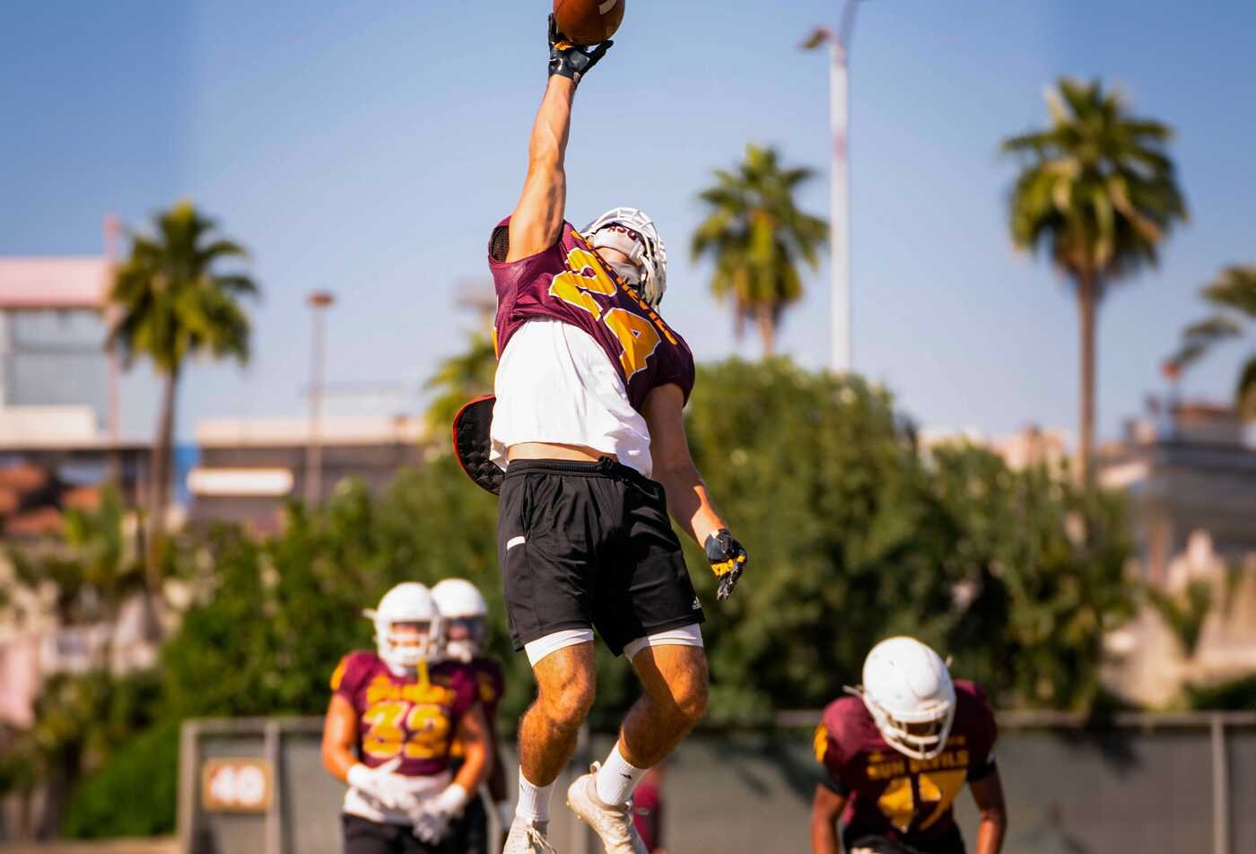 An athlete reaches for a football at practice, demonstrating an area explored in ASU's Counseling and Applied Psychological Science (Sport and Performance Counseling), BS program.