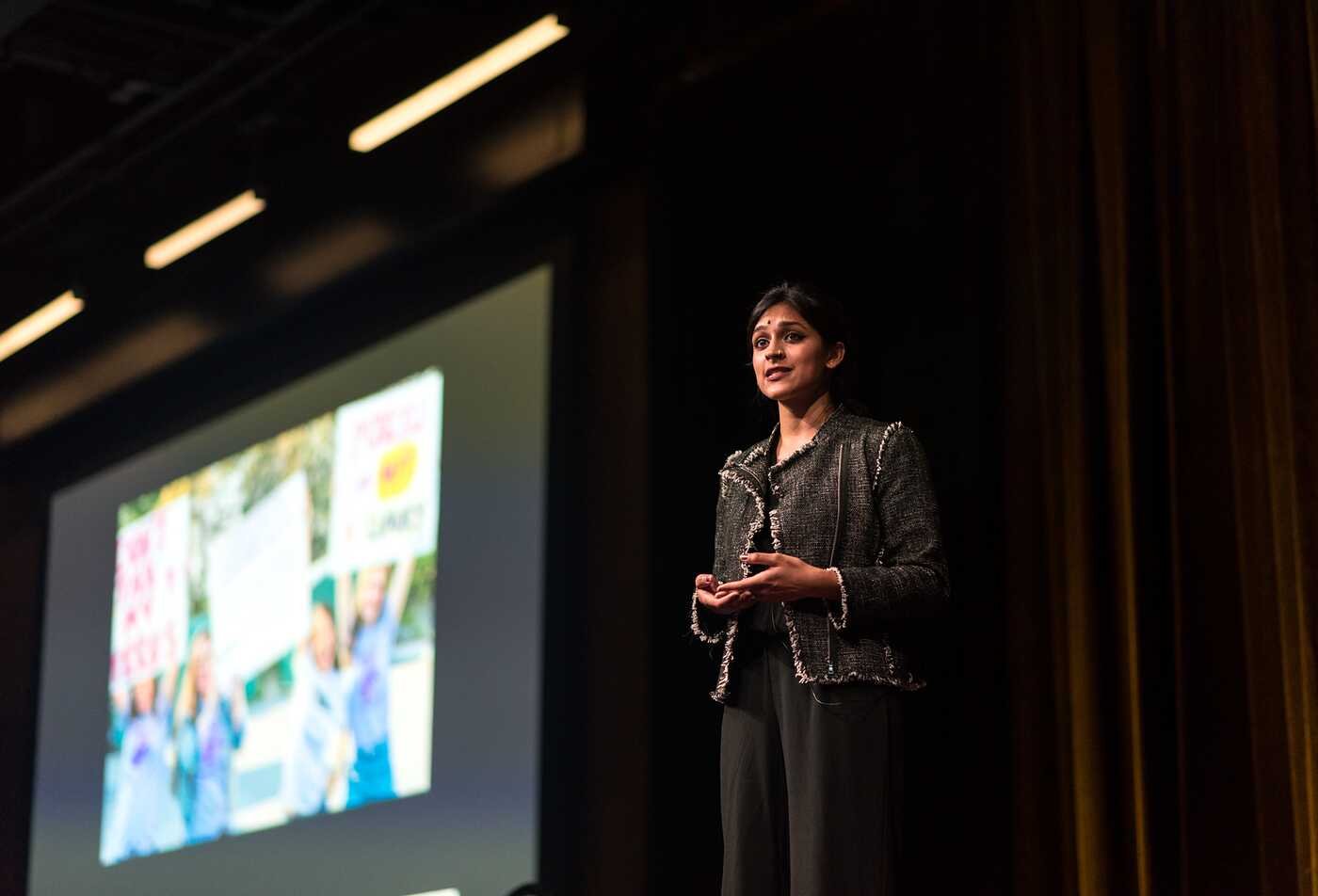 Speaking on stage beside a presentation screen, a presenter demonstrates communication skills central to ASU’s Communication minor