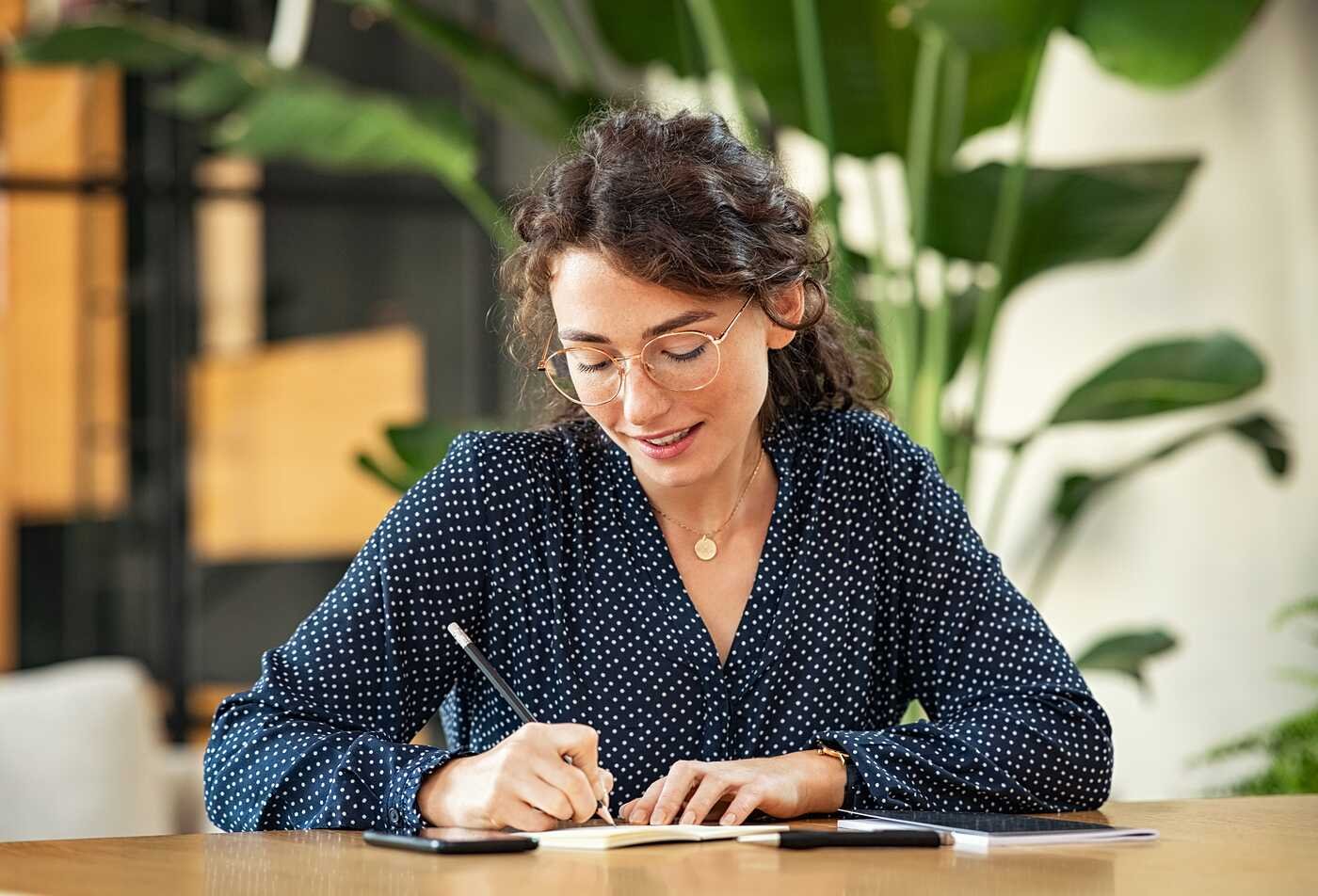 A student writes at a desk, reflecting literary study and composition in ASU's English, BA program.