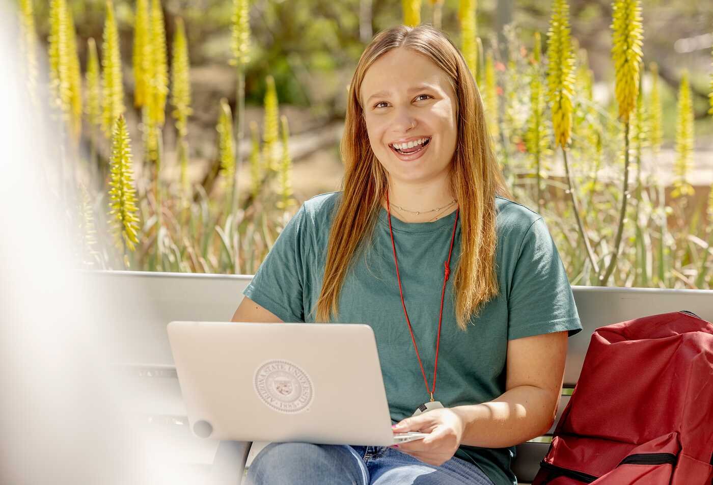A student works outdoors on a laptop, connecting culture and nature in ASU's Environmental Humanities certificate.