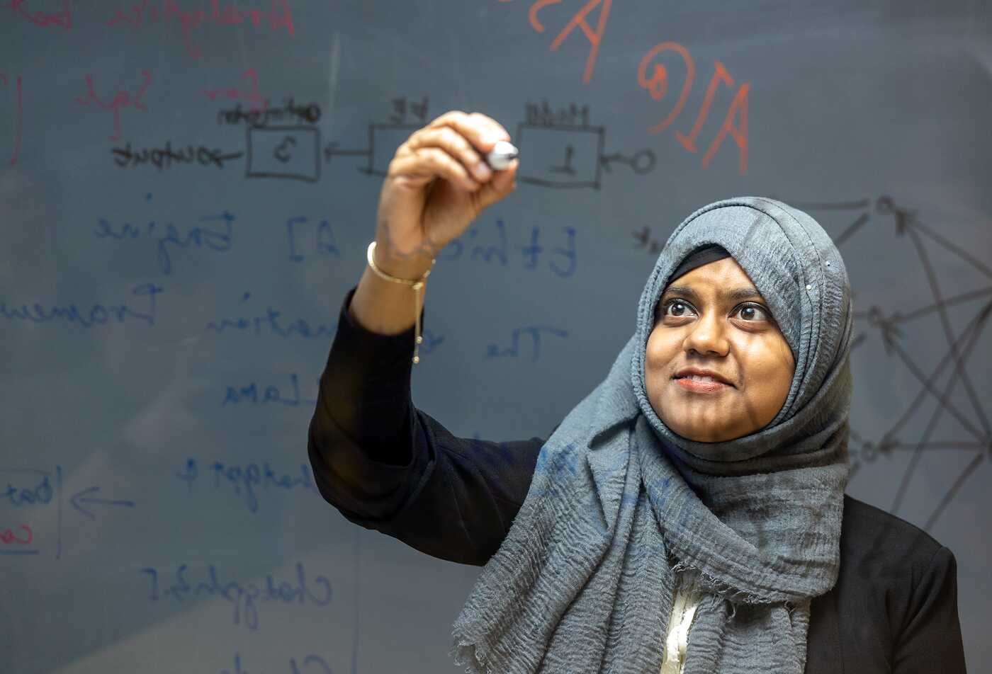 Writing equations on a transparent board, a student explores mathematical models central to ASU’s Applied Mathematics program