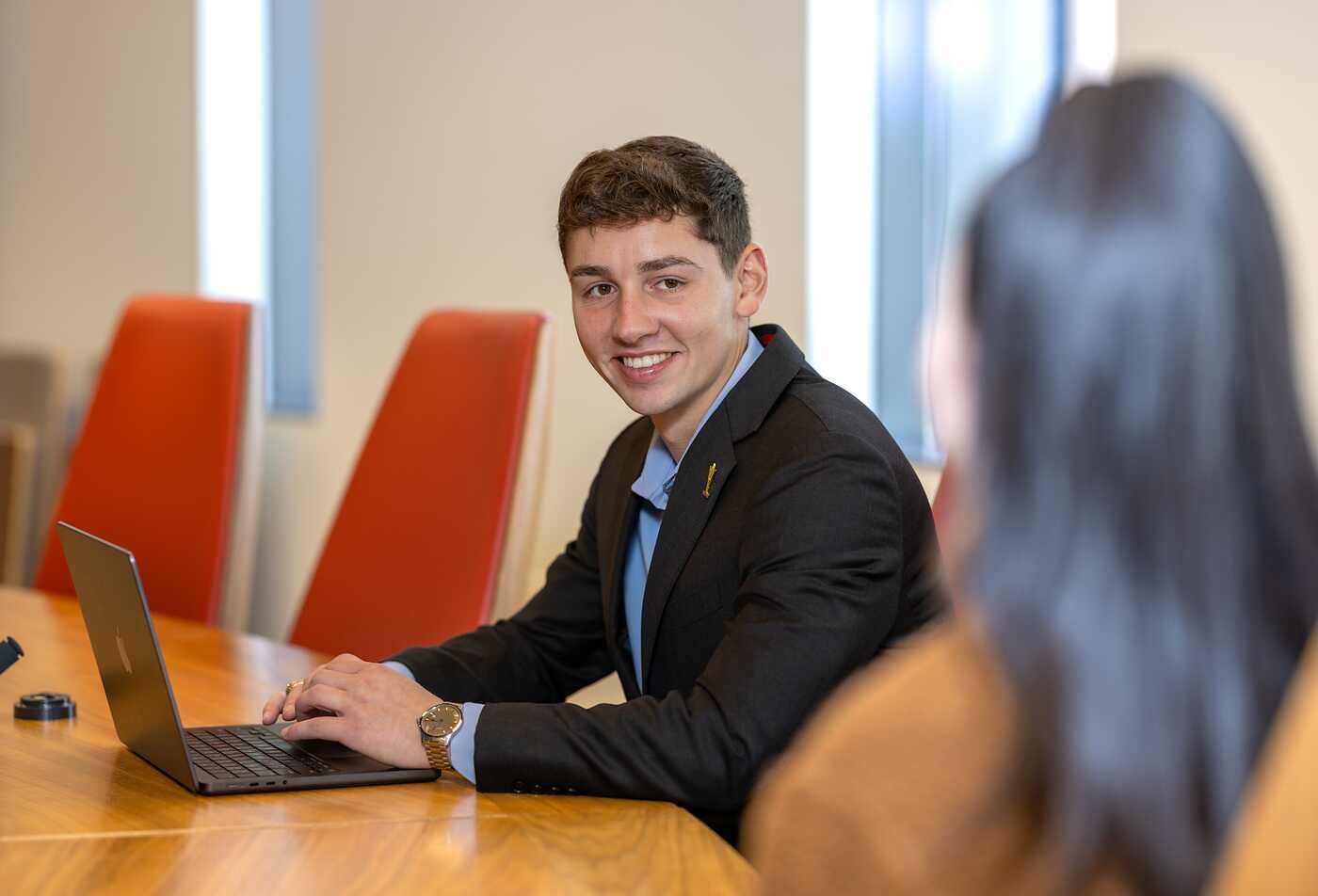 A professional collaborates with a colleague at a conference table, developing leadership skills in ASU's Organizational Leadership, AA program.