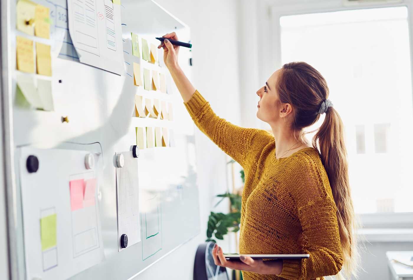A professional organizes tasks on a planning board, demonstrating project coordination in ASU's Project Management, BS program.