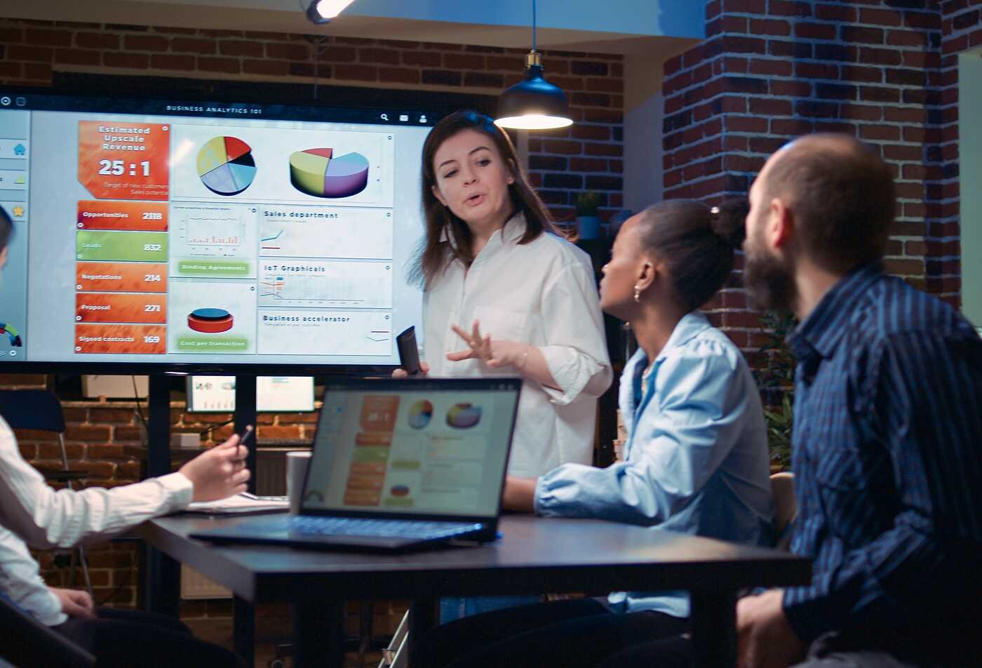 A presenter discusses data dashboards with a team, highlighting visual information in ASU's Technical Communication (Data Visualization), BS program.