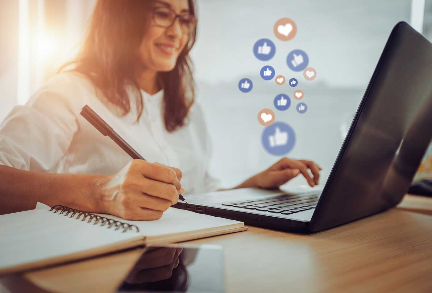 A professional uses a laptop with social media icons, reflecting strategy in ASU's Technical Communication (Social Media Management), BS program.