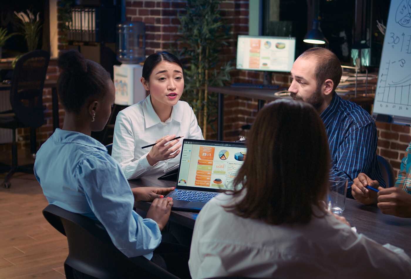 Professionals collaborate around a laptop, developing clear digital content in ASU's Technical Communication minor.