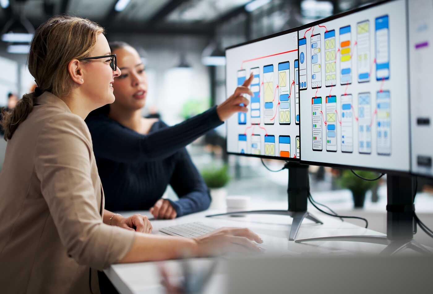 Designers review digital interfaces on large screens, demonstrating user-centered design in ASU's User Experience, BS program.