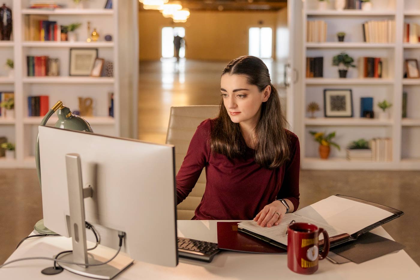 A student engages in research work at a desk with a computer and books, illustrating practical skills in ASU's Master of Legal Studies program.