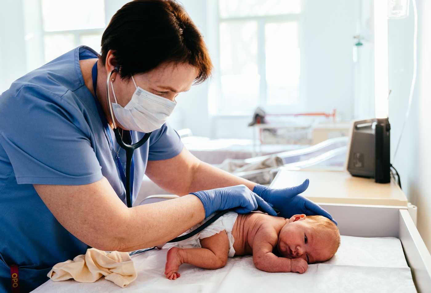 A pediatric nurse practitioner examines a newborn during a neonatal health assessment, representing the field explored in the Acute Care Pediatric Nurse Practitioner (Graduate Certificate).