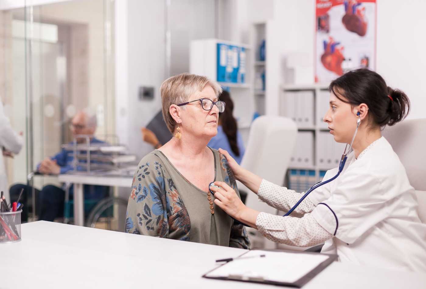 A nurse practitioner performs a health assessment for an older adult patient during a clinic visit, representing the field explored in the Adult Gerontology Nurse Practitioner (Graduate Certificate).