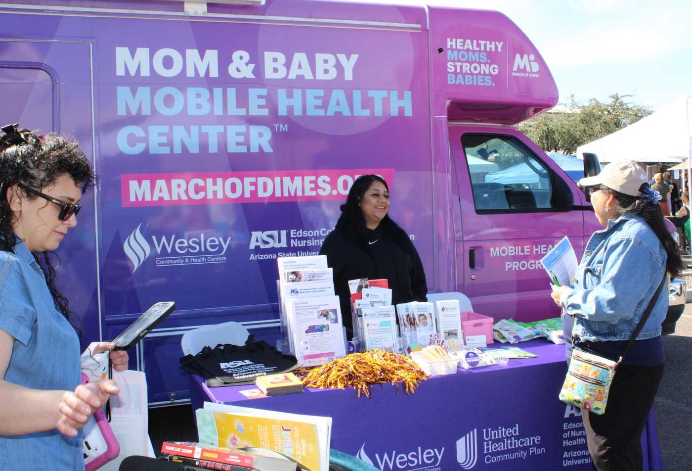 A student shares health resources with a community member at an outreach event, reflecting community connection in the minor in Community Health.
