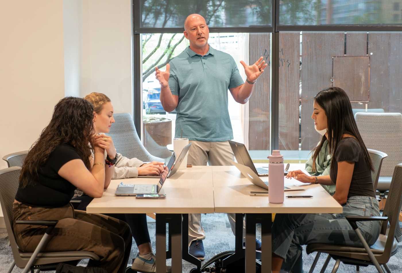 A faculty member leads a discussion with students during a collaborative class session, showcasing teamwork in the Healthcare Innovation, MHI.